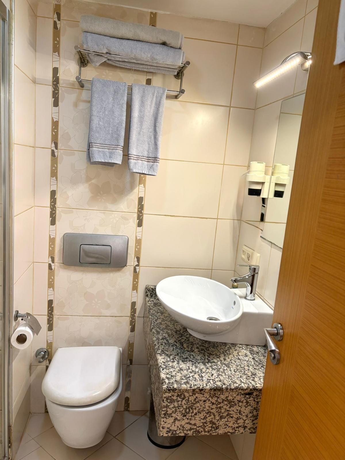 Un baño con inodoro, lavamanos y toallero.