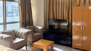 A modern living room with a sofa, a coffee table, a flat-screen TV, and a wardrobe. - Pinar Elite Hotel (Adana)
