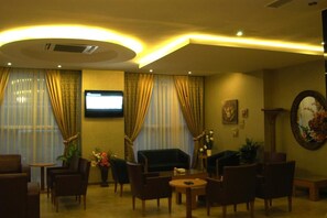 A hotel lobby with a television, seating area, and decorative elements. - Pinar Elite Hotel (Adana)