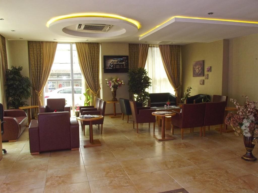 Een hotellobby met een zithoek, een televisie en een groot raam.