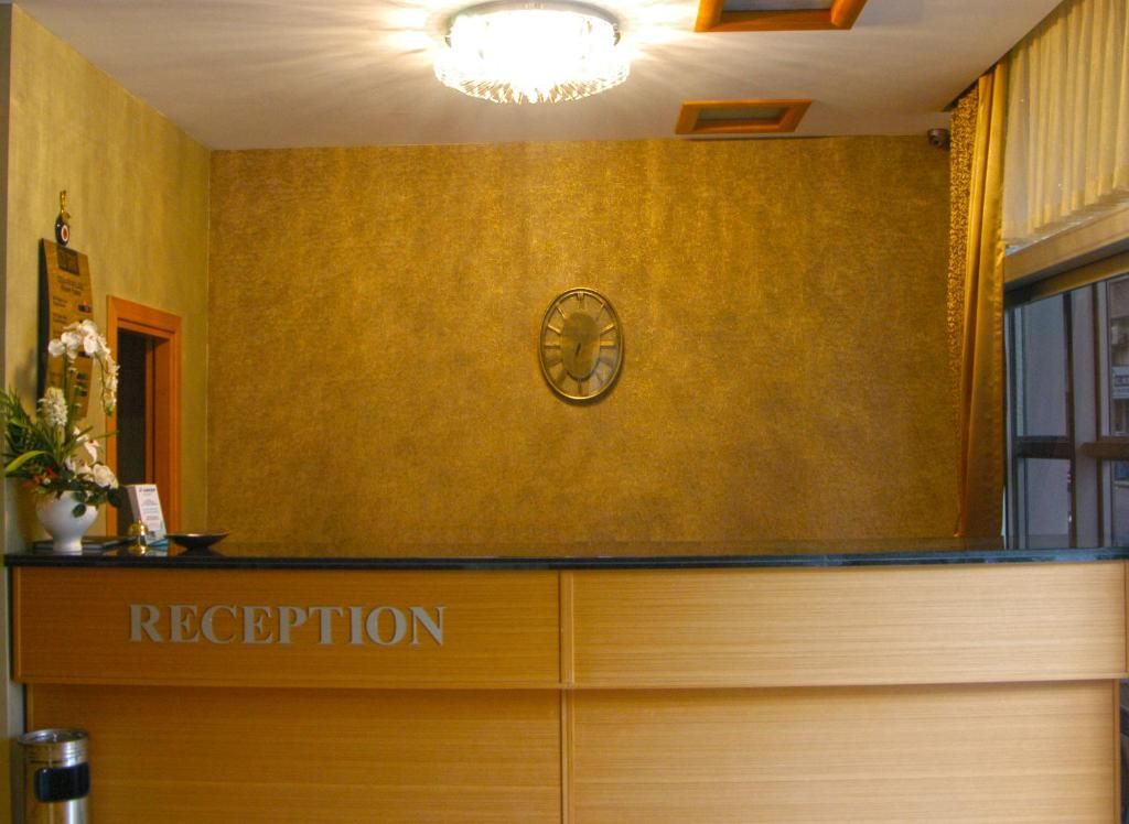 A reception area with a clock, a reception desk, and a potted plant.