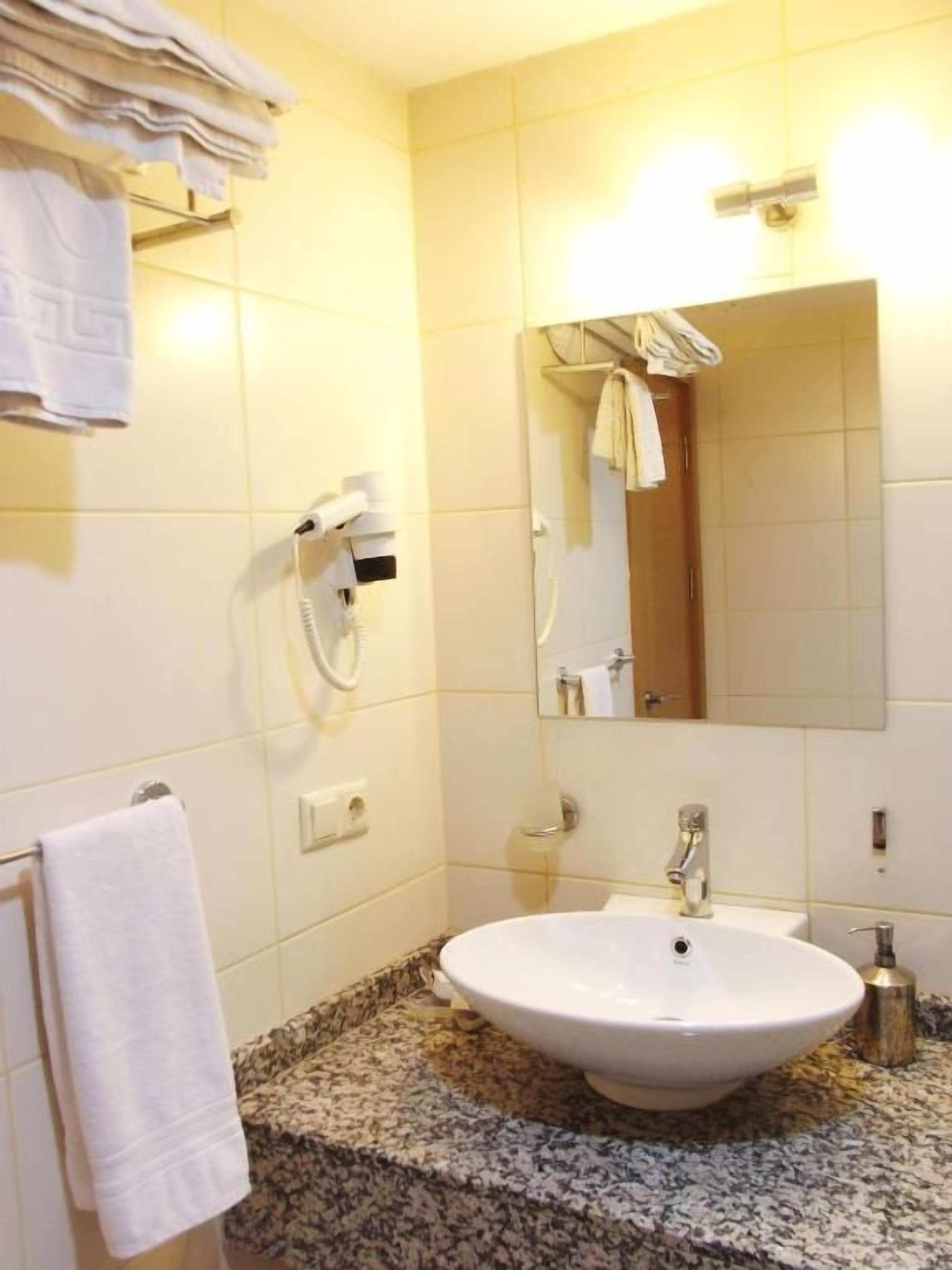 A bathroom with a sink, mirror, towel rack, and hairdryer.