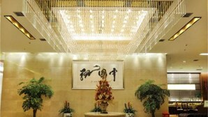 A lobby with a large chandelier, a central table with a floral arrangement, and potted plants. - Shi Dai Jin Cheng Hotel (Chengdu)