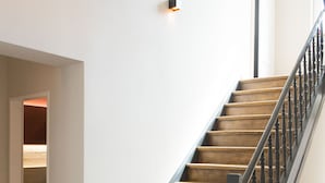 A wooden staircase with a black handrail leading to an upper floor. - Cottage Rheingau Hotel (Walluf)