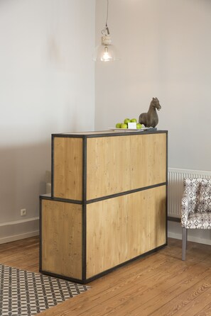 A wooden cabinet with a black frame, a hanging light fixture, and a chair with a patterned cushion. - Cottage Rheingau Hotel (Walluf)