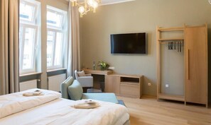 A hotel room with two beds, a desk, a TV, and a wardrobe.