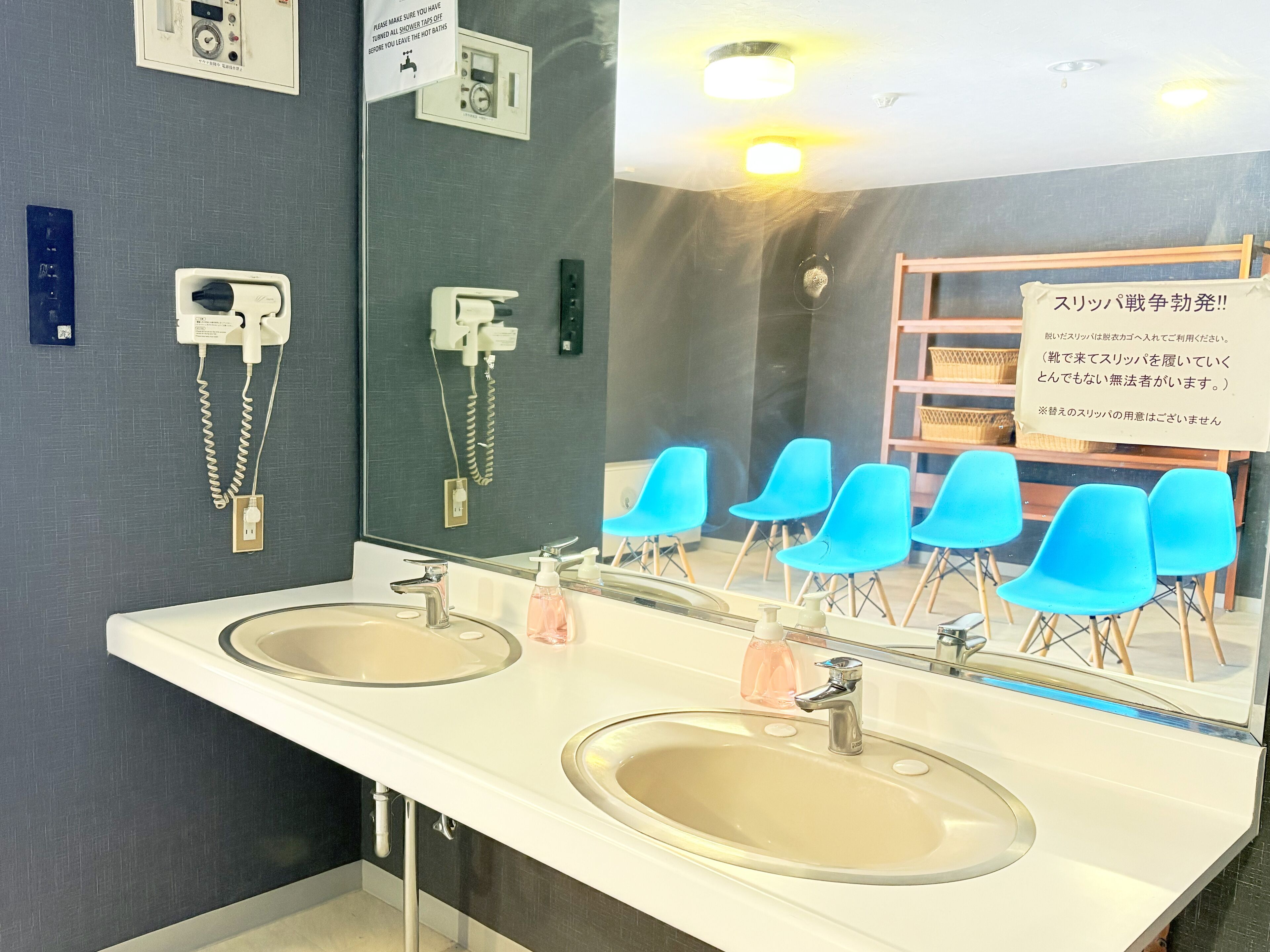 Un baño moderno con dos lavabos, un espejo y un letrero en japonés.