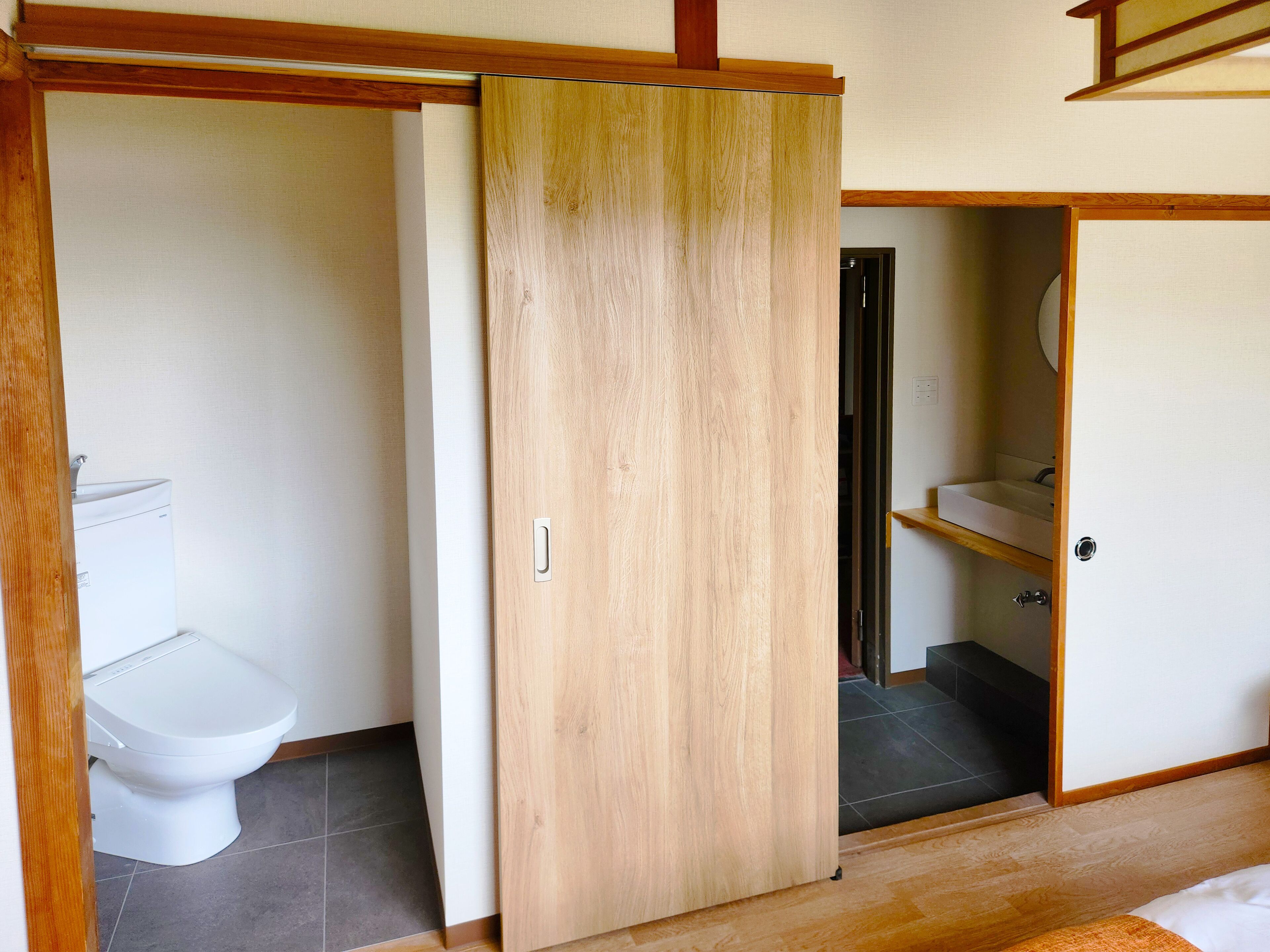 Ein Badezimmer mit Toilette, einer Holztür und einem Waschbecken.