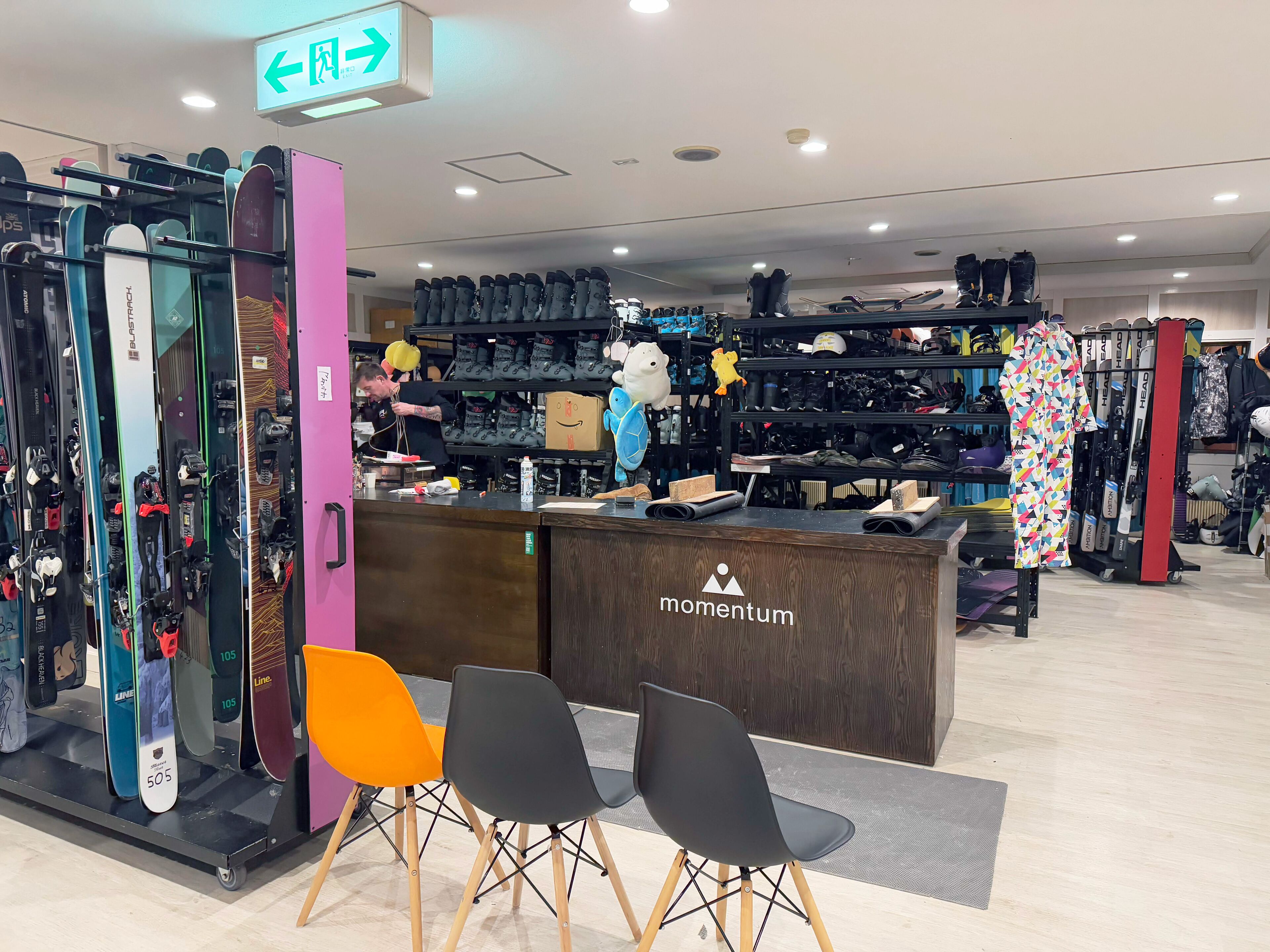 A shoe store with a reception desk, shelves of shoes, and a few chairs in the foreground.