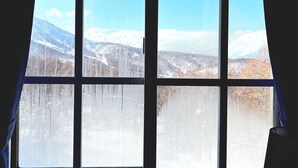 Una ventana con vista a un paisaje nevado y montañas.