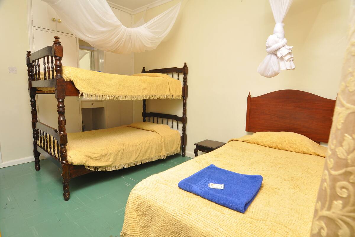 A room with bunk beds, a bedside table, and a hanging mosquito net.