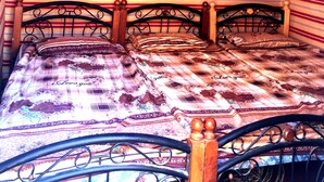 Una habitación con un patrón a rayas en la pared, una cama con un edredón estampado y una ventana pequeña con marco cuadrado.