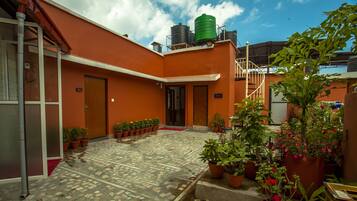 Un patio con plantas en macetas, suelo de baldosas y una escalera que sube a un nivel superior.