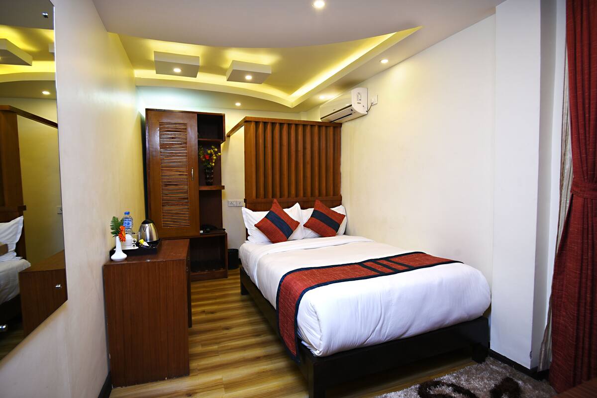 A hotel room with a bed, wooden headboard, bedside table, and a mirror.