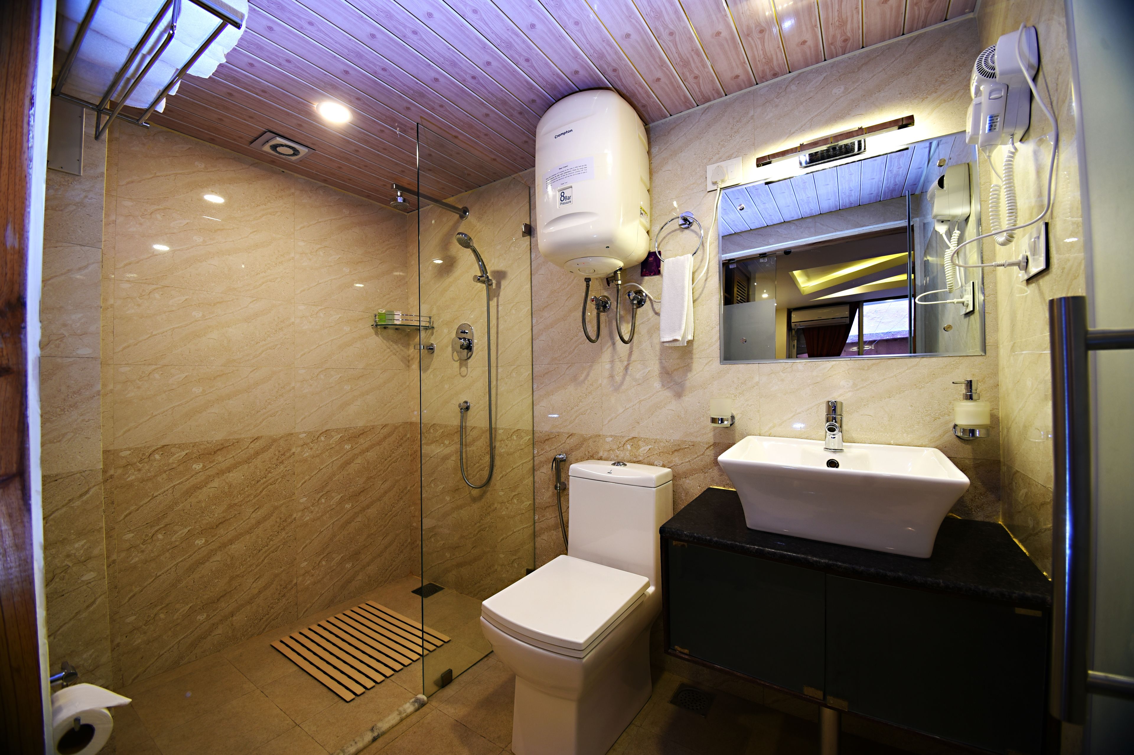 A modern bathroom with a glass-enclosed shower, a white toilet, a sink with a black countertop, and a mirror above the sink.