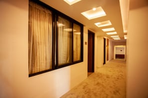 Stroll through the hotel's carpeted corridors, lined with light-colored walls and natural light from the window.