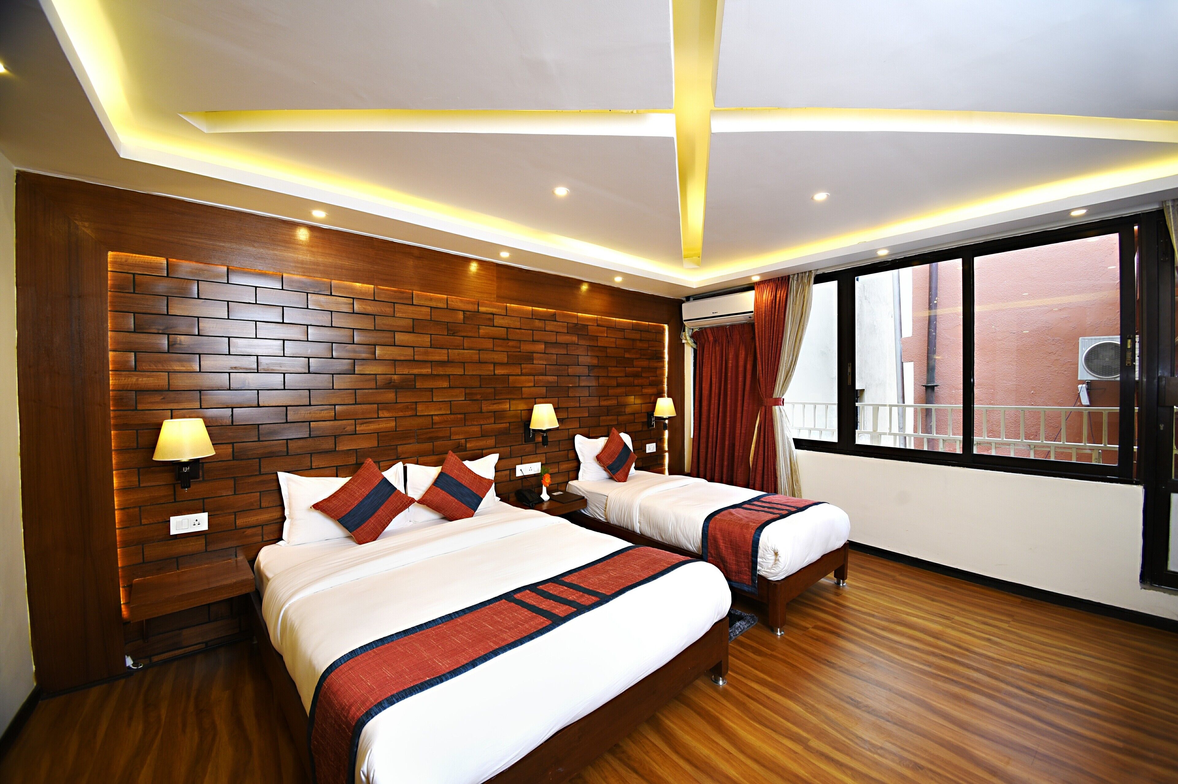 Une chambre d’hôtel avec deux lits, une tête de lit en bois et une grande fenêtre donnant sur un beau paysage.