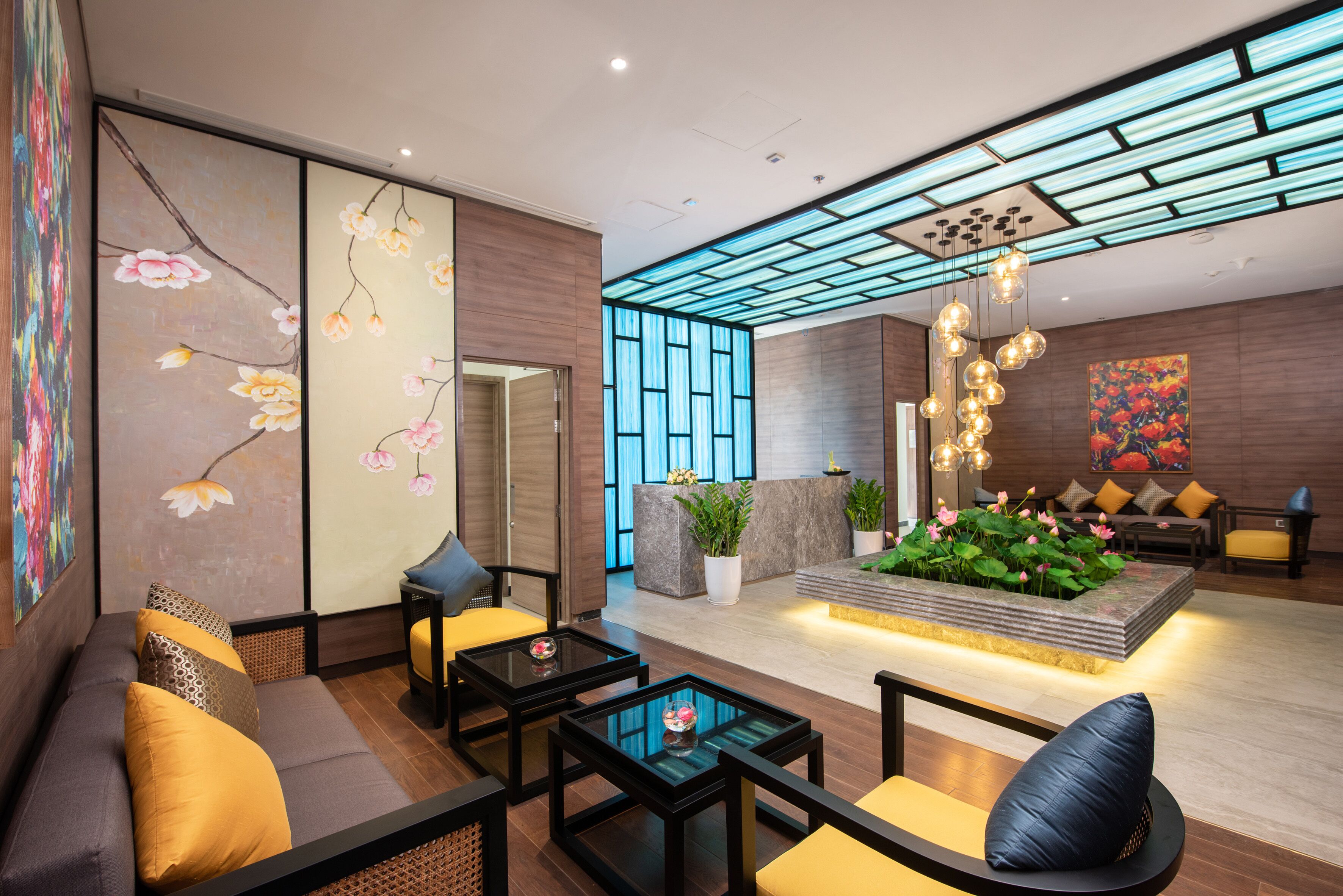 Een moderne lobby met een receptiebalie, een zithoek en een decoratieve plantenpresentatie.