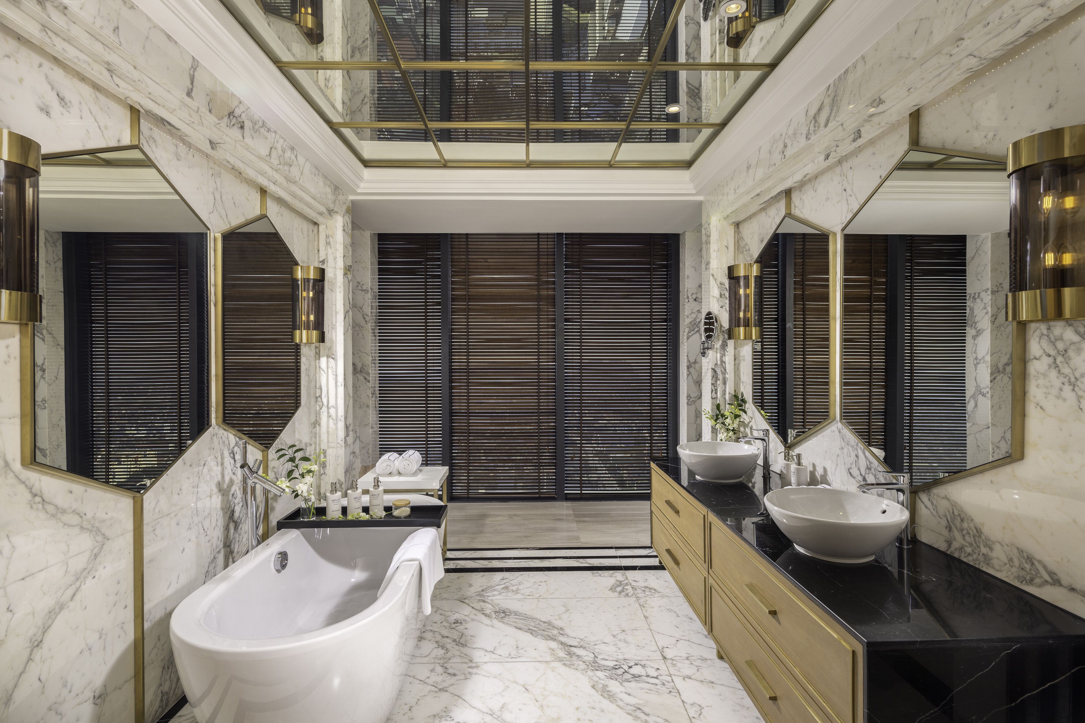 Un baño lujoso con una bañera independiente, un espejo grande y un lavabo doble.
