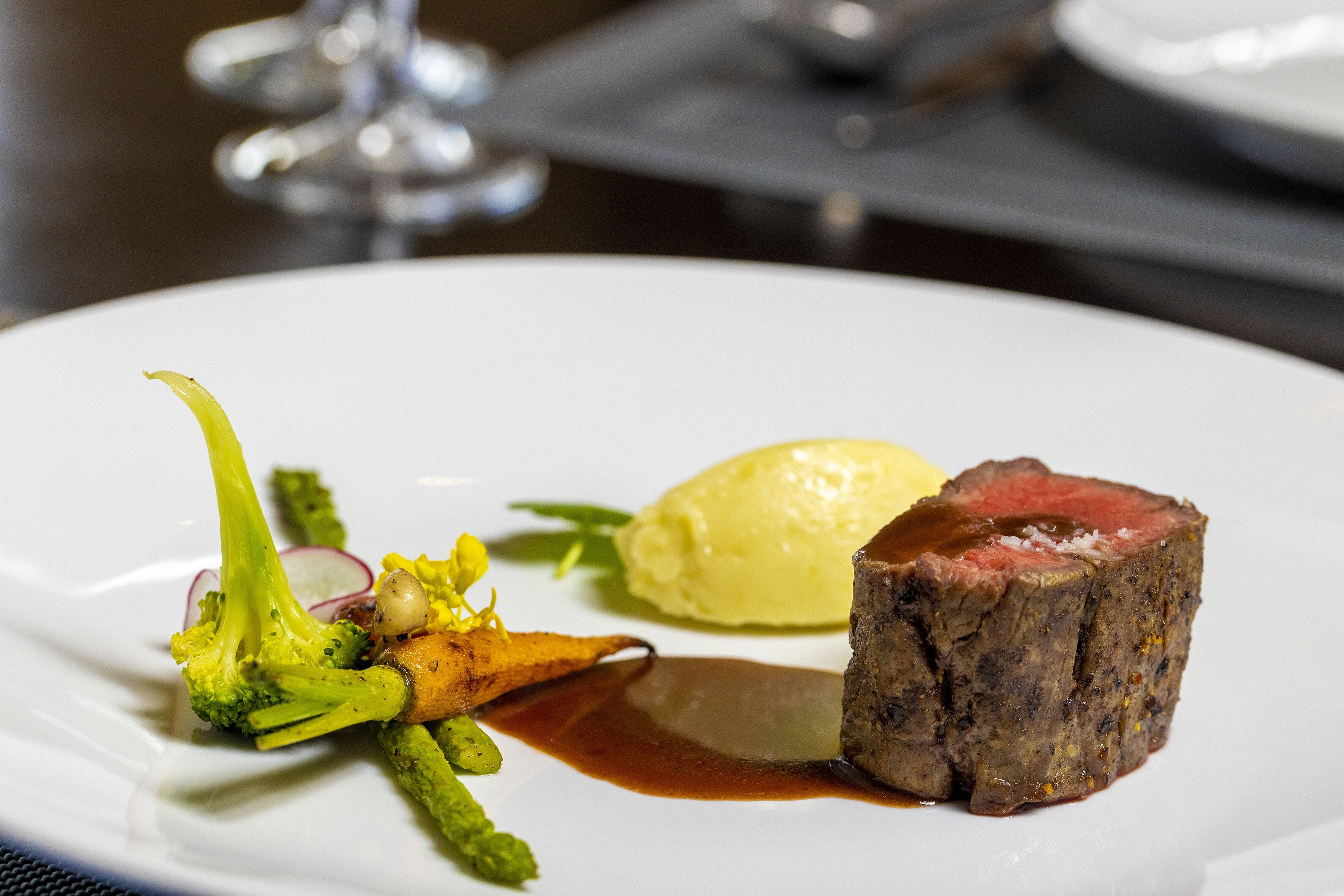 Un plato de comida con bistec, brócoli y un puré amarillo.