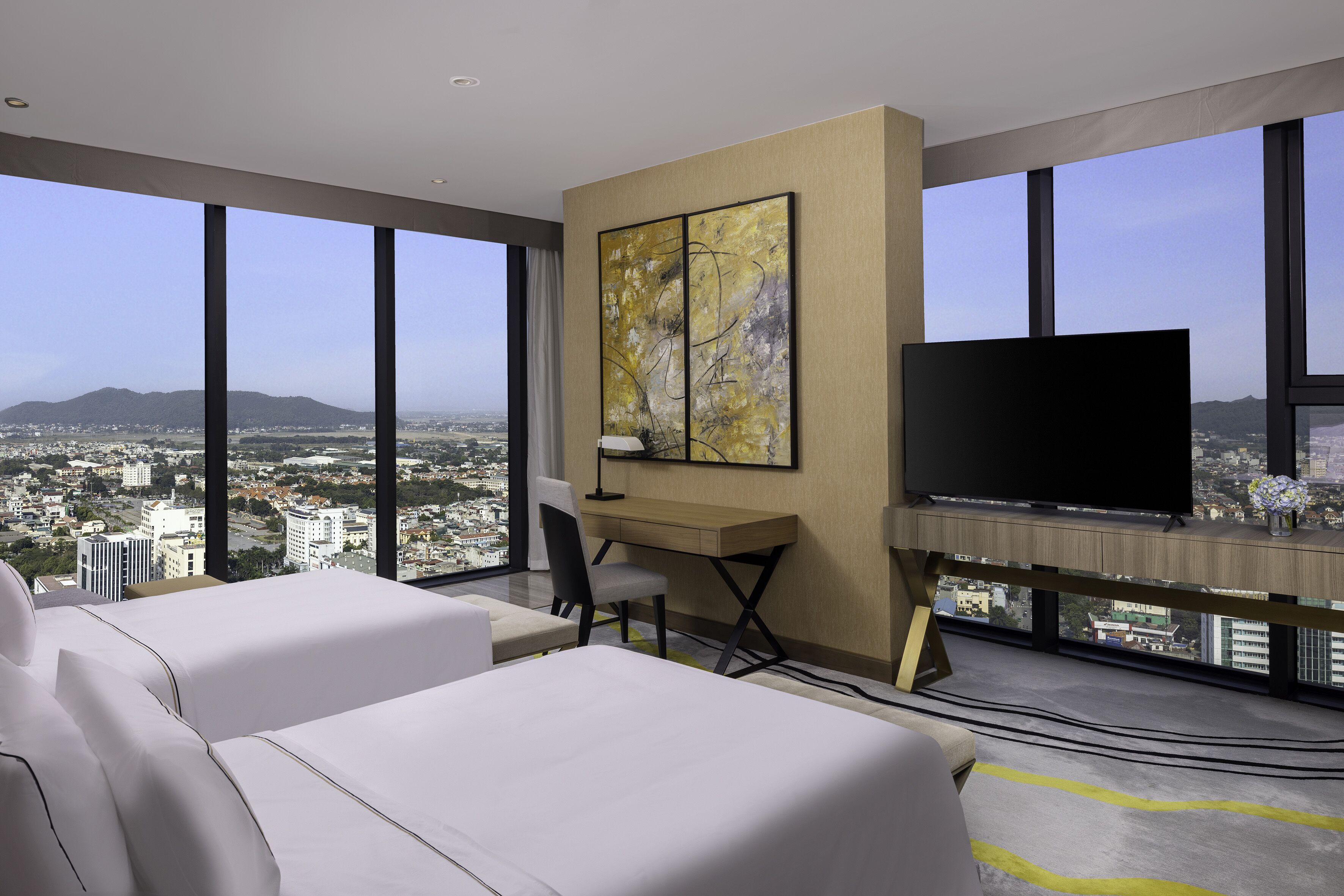 Habitación de hotel con una ventana grande, escritorio, silla, cama y televisor de pantalla plana.