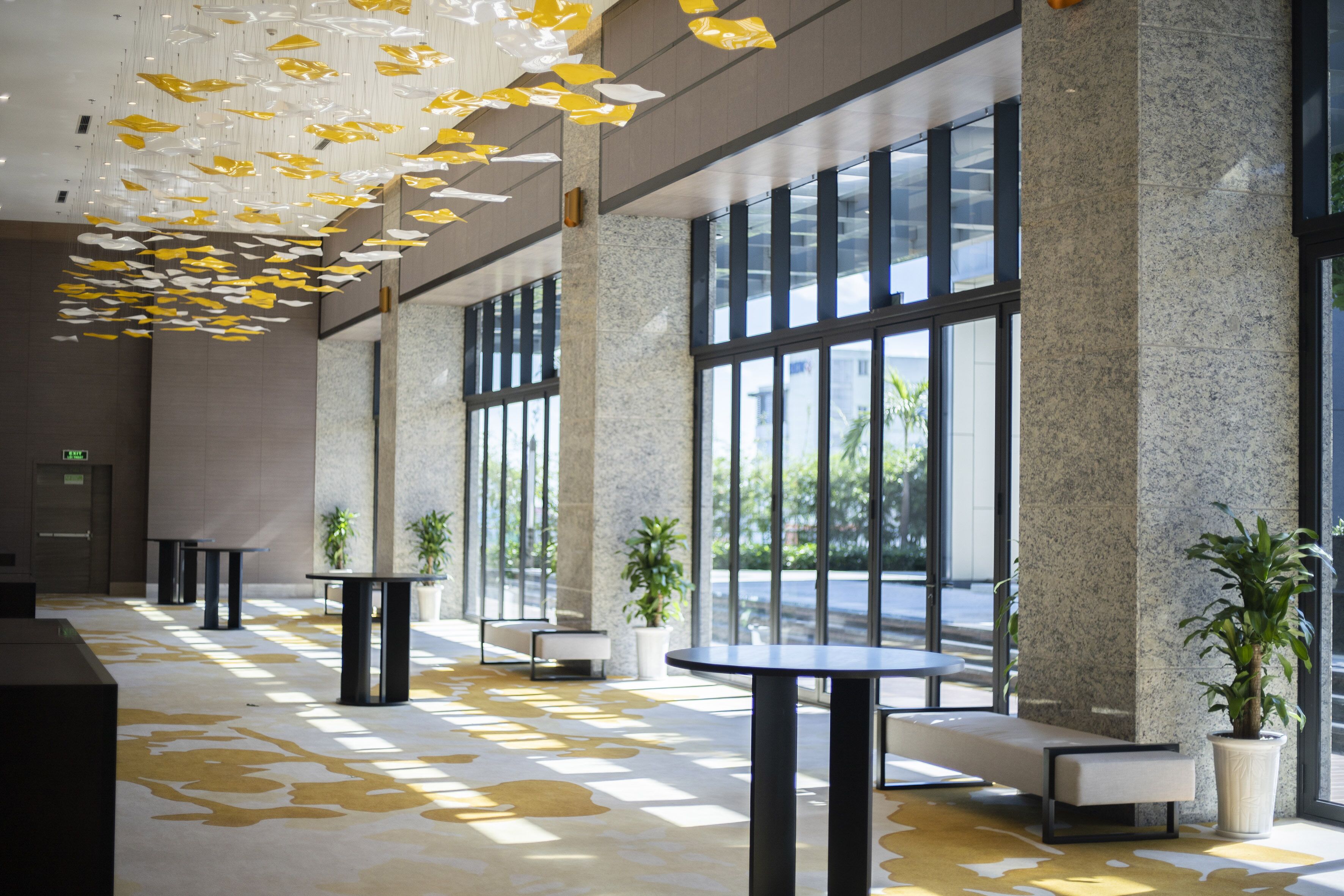 Een ruime lobby met grote ramen, modern meubilair en hangende decoraties.