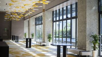 A spacious lobby with large windows, modern furniture, and hanging decorative elements.