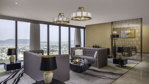 A modern living room with a sofa, coffee table, and lamps. There is a large window with a view of the city. - Meliá Vinpearl Thanh Hoa (Hac Thanh)