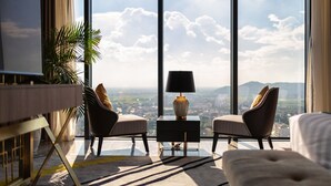 A modern hotel room with a large window, two armchairs, a small side table with a lamp, and a sofa. - Meliá Vinpearl Thanh Hoa (Hac Thanh)