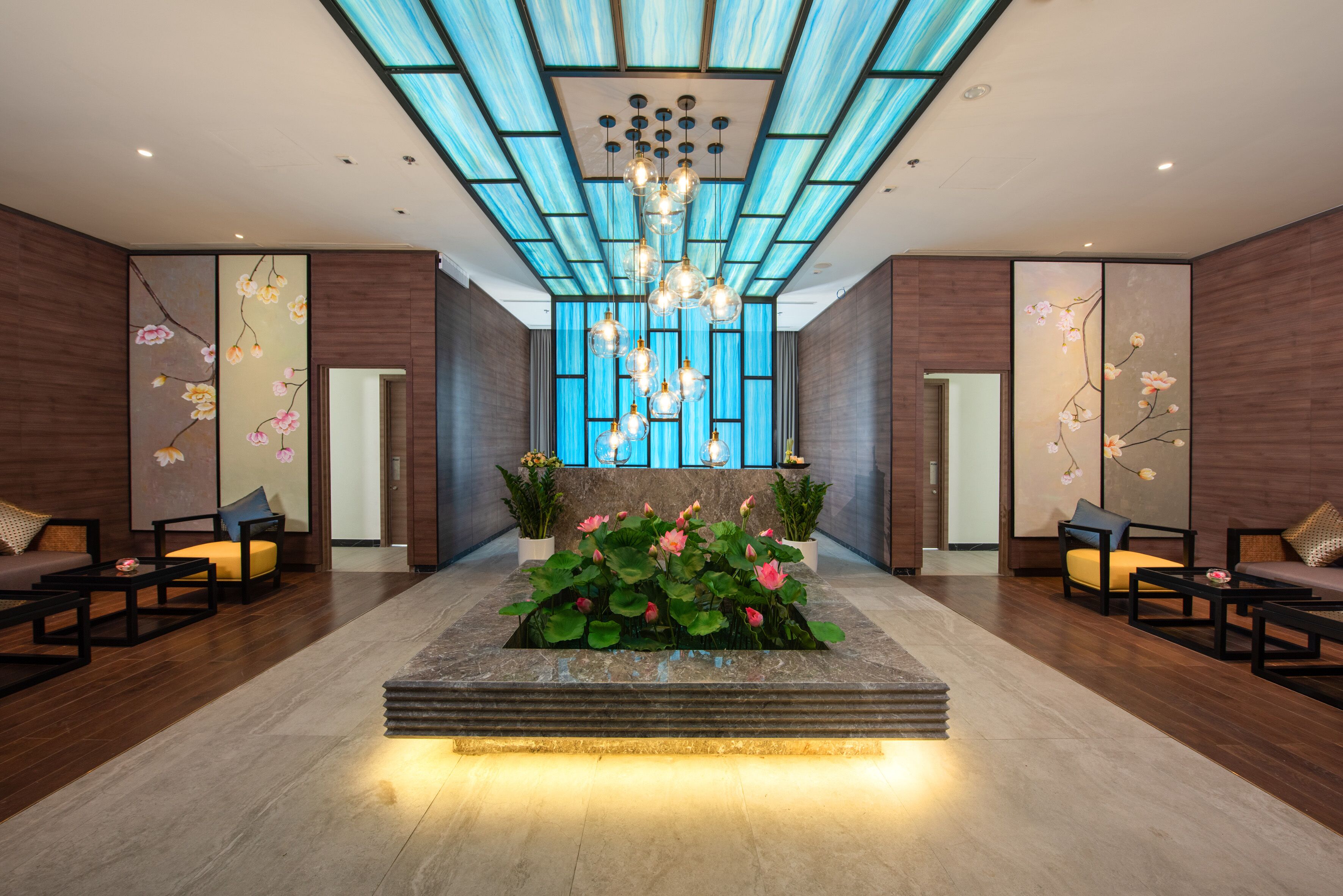 A modern lobby with a central water feature, seating areas, and a unique ceiling design.