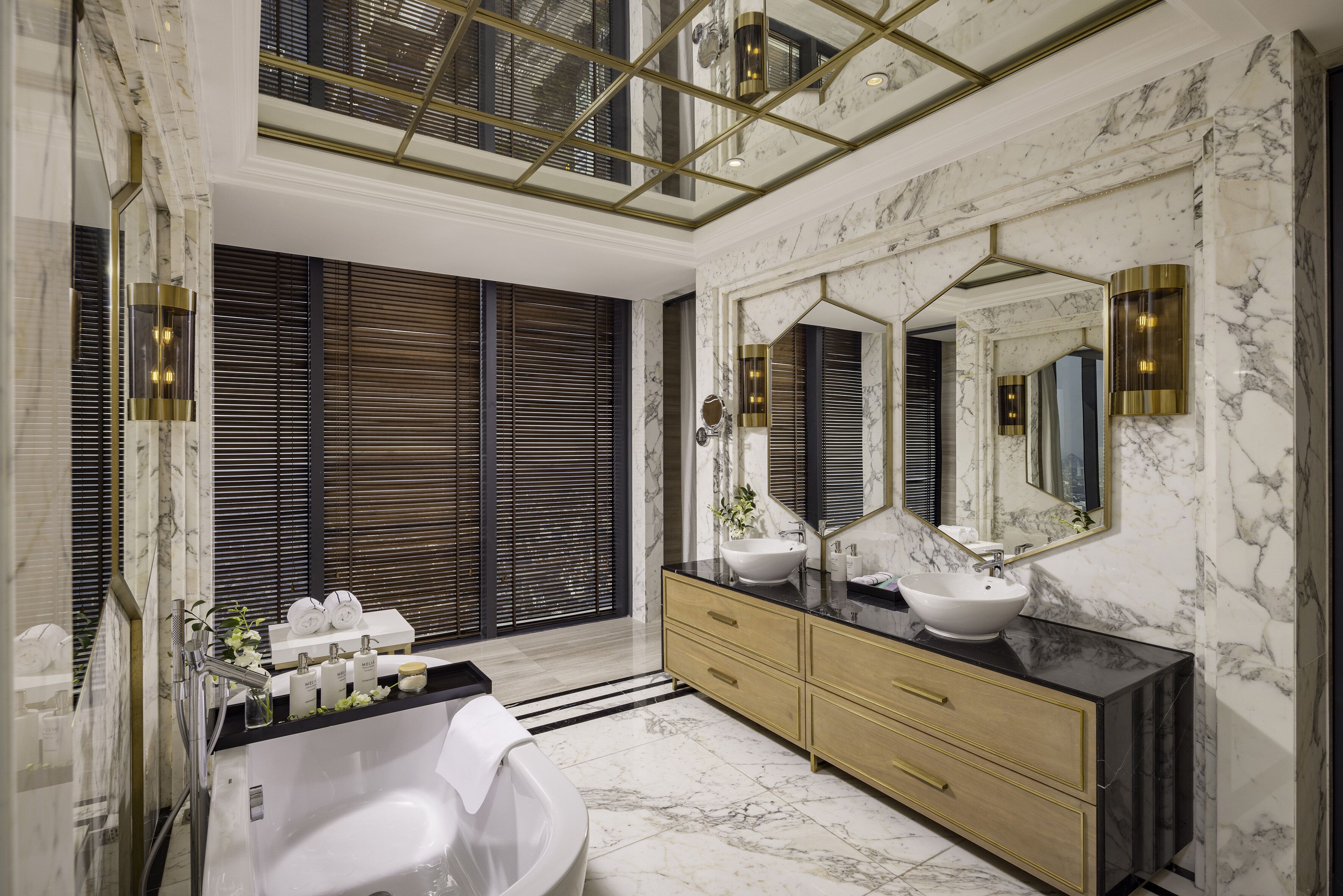 A modern bathroom with a large bathtub, two sinks, and a vanity with drawers.