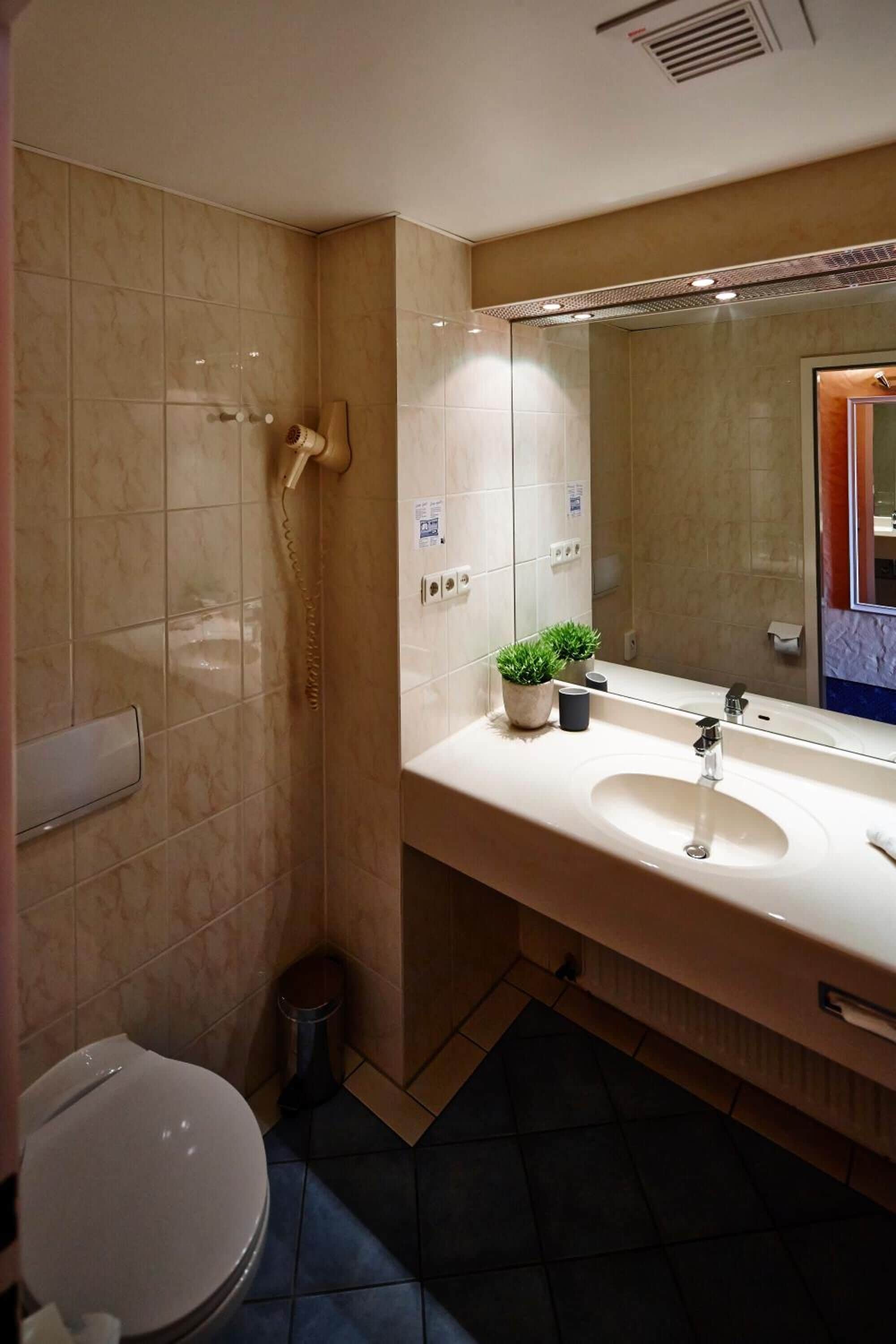 A modern bathroom with a shower, toilet, and sink.