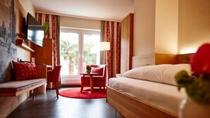Une chambre d’hôtel avec un lit, un bureau, une chaise, une télévision et une fenêtre avec des rideaux.
