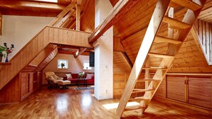 Un vaste loft doté d’un plafond haut, de poutres en bois et d’un toit en pente.