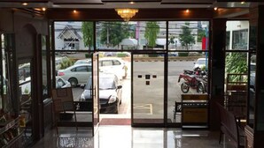 Um saguão de hotel com piso lustroso, um candelabro e vista para carros e motocicletas estacionados do lado de fora.