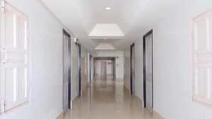 Um corredor comprido e estreito, com paredes brancas e portas de ambos os lados.