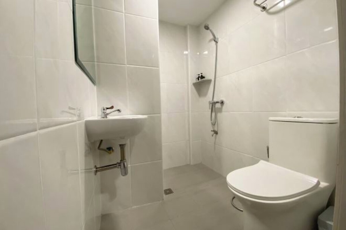 A small, modern bathroom with a white toilet, a sink, and a shower.