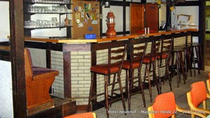 A bar area with wooden shelves, multiple glasses, and a bulletin board. - Hotel Heidehof (Unna)