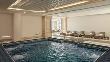 Un espace bien-être comprenant un jacuzzi, des chaises longues et un sol carrelé.