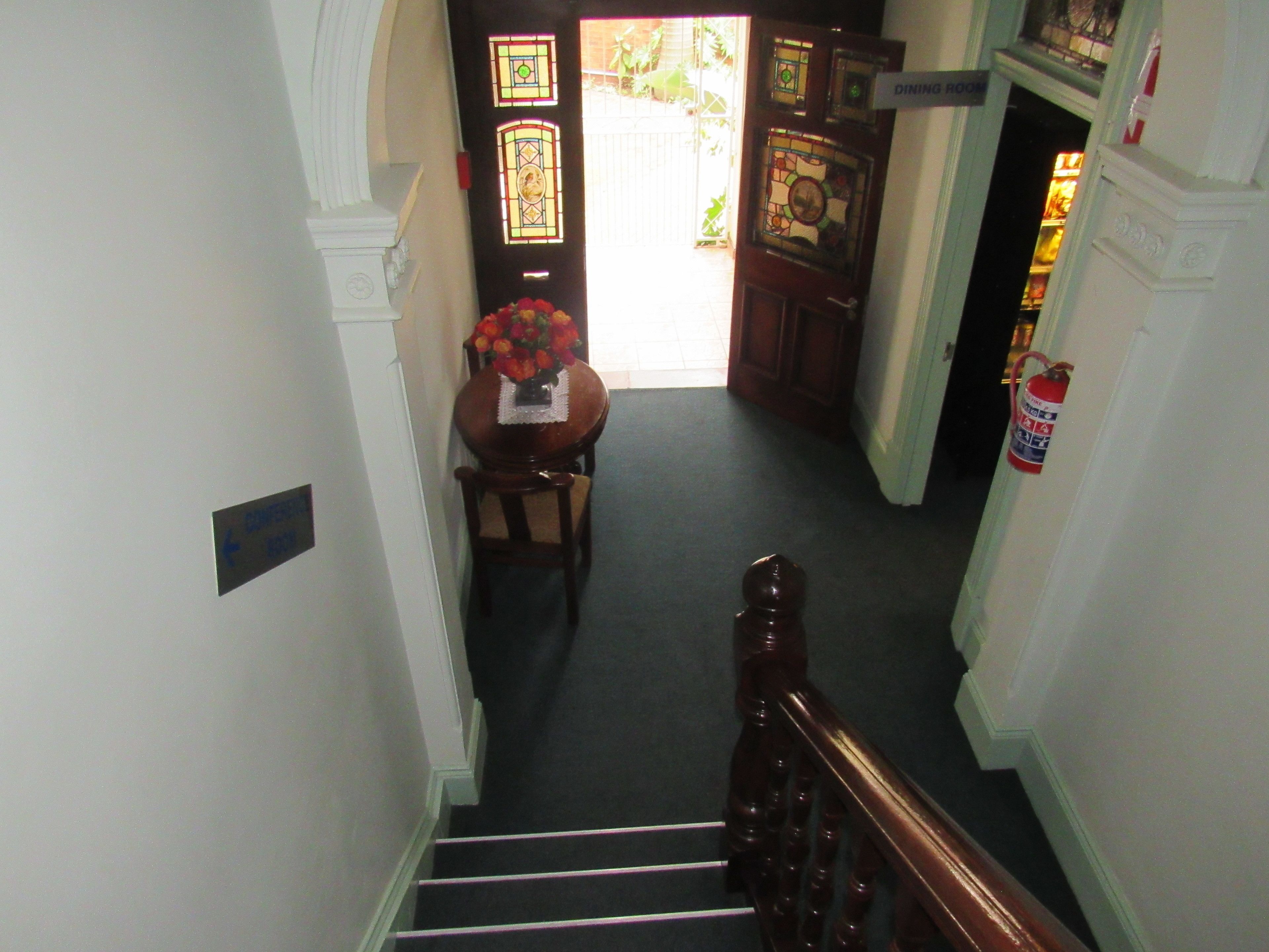 A staircase leading to a dining room with a table set for two and a vase of flowers.