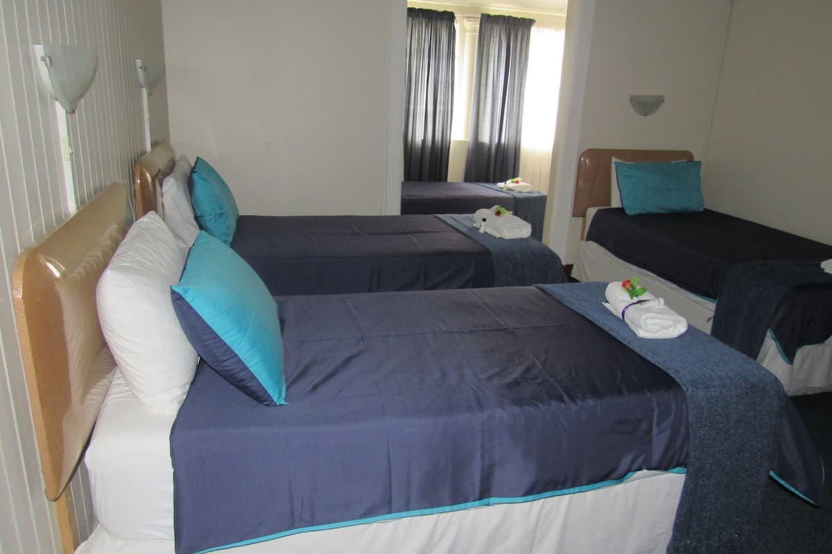 A hotel room with two single beds, each with a pillow and a towel.
