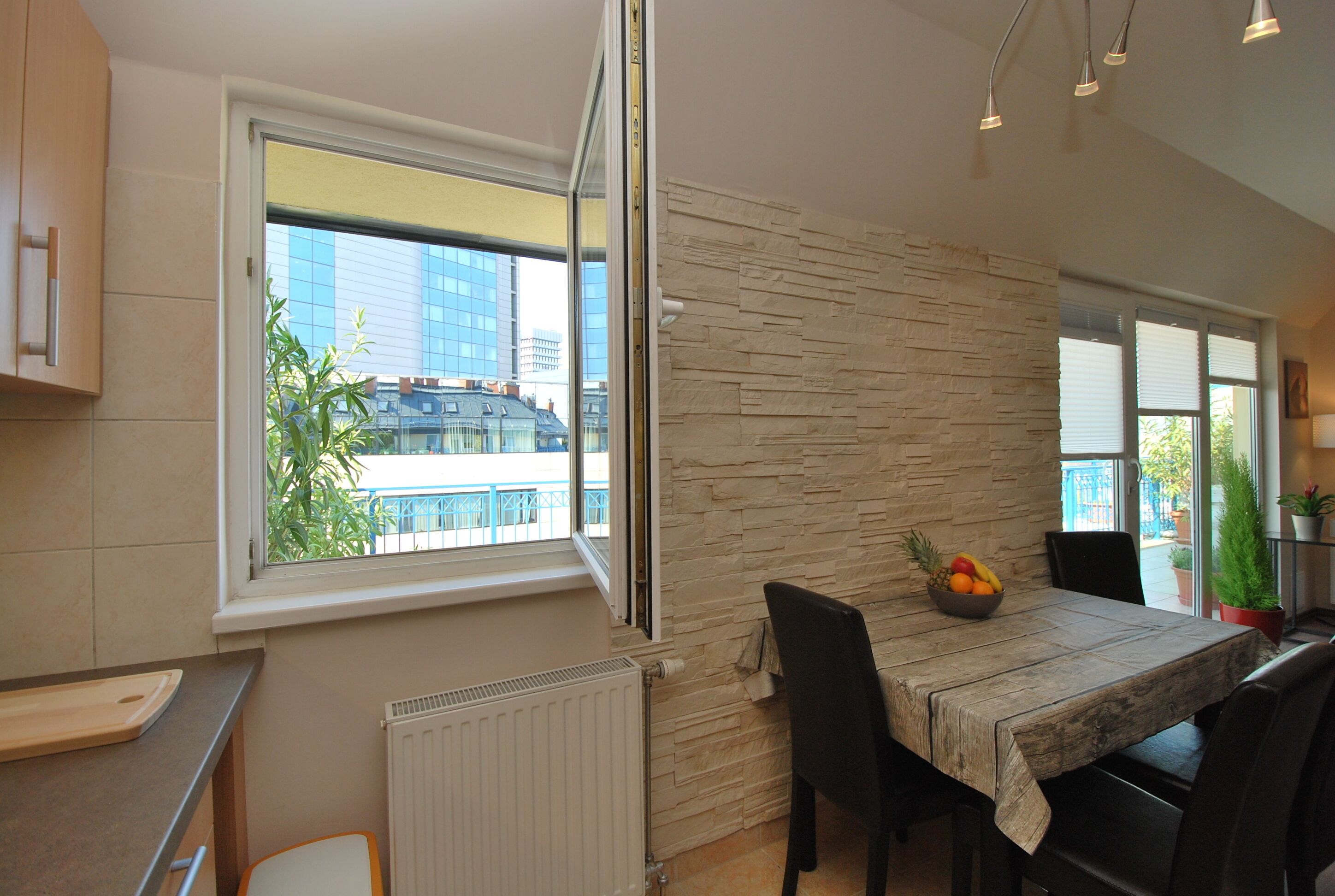A modern kitchen with a large window, a stone accent wall, and a dining area with a table and chairs.