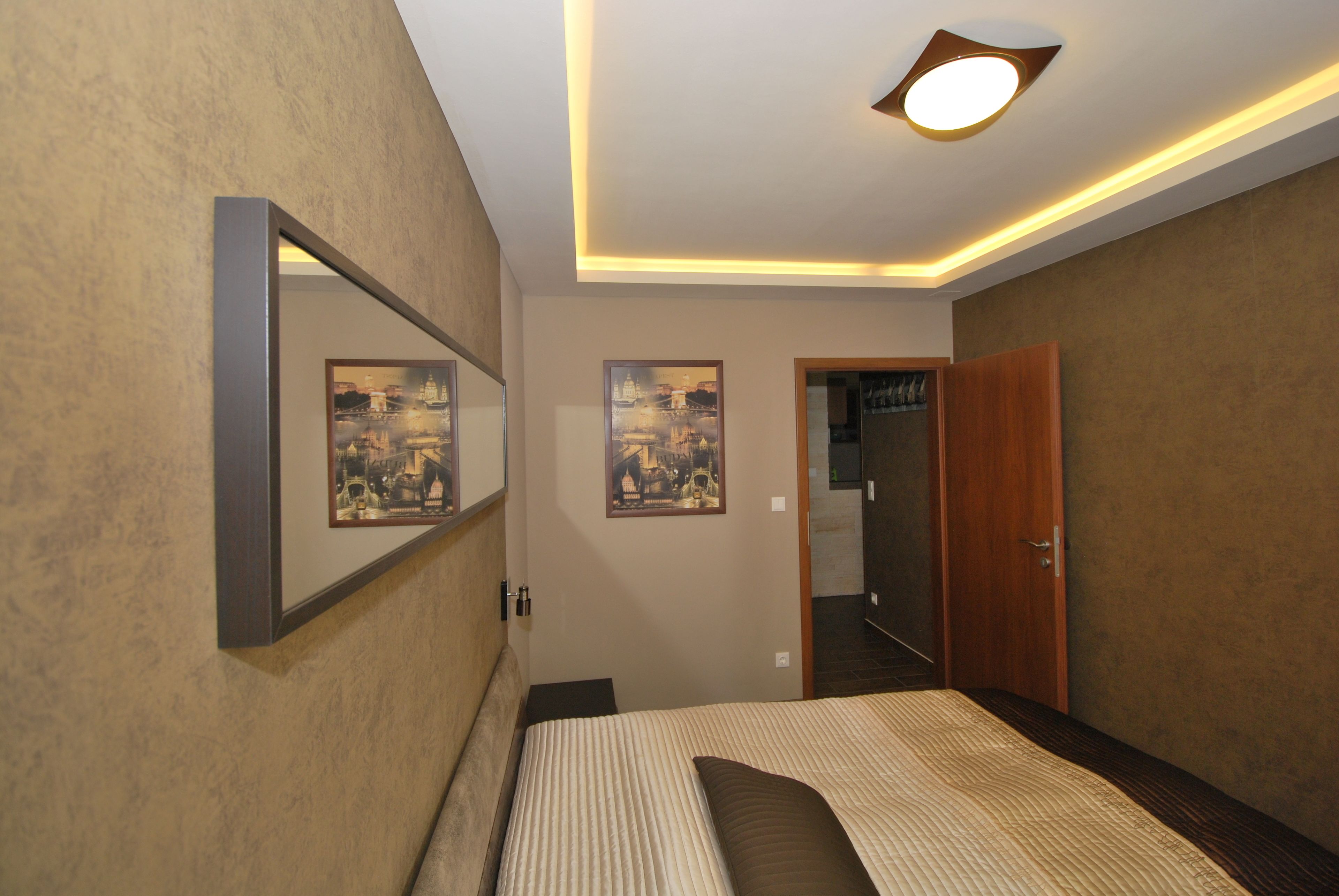 A bedroom with a bed, a mirror, and two framed pictures on the wall.