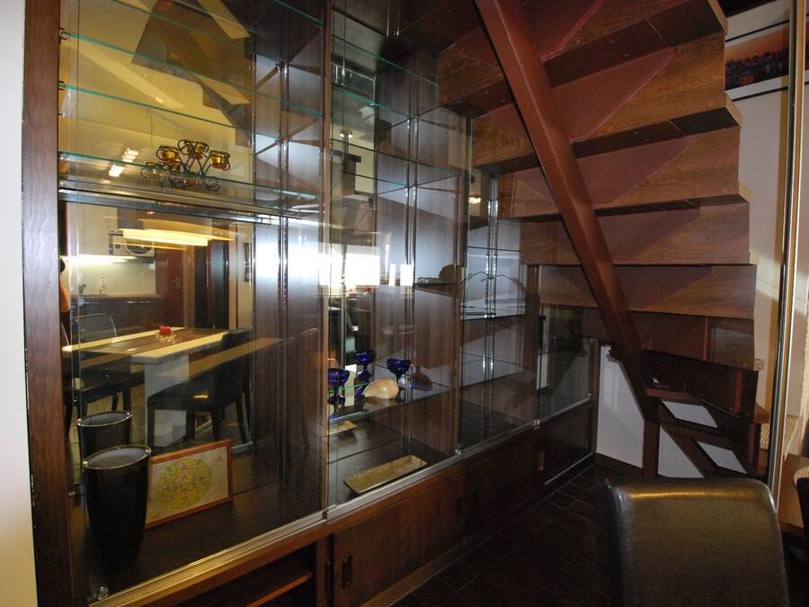 Una cocina moderna con armarios de vidrio, una escalera de madera y un comedor con sillas y una mesa.