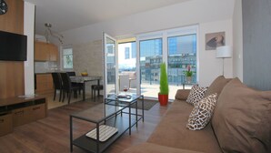 Un salon moderne avec une table basse en verre, un canapé marron et un coin repas comprenant une table et des chaises.