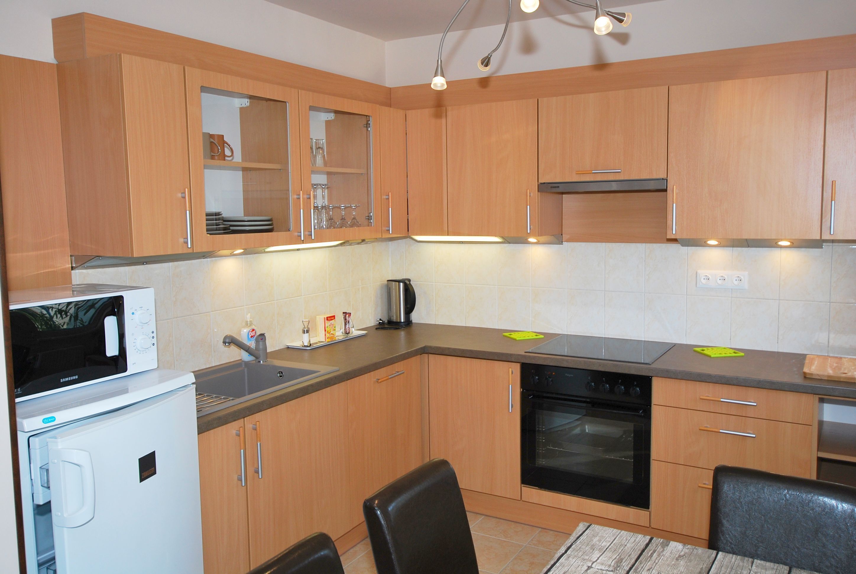 A compact kitchen with wooden cabinets, a microwave, a sink, and a stove.