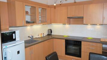 A compact kitchen with wooden cabinets, a microwave, a sink, and a stove.