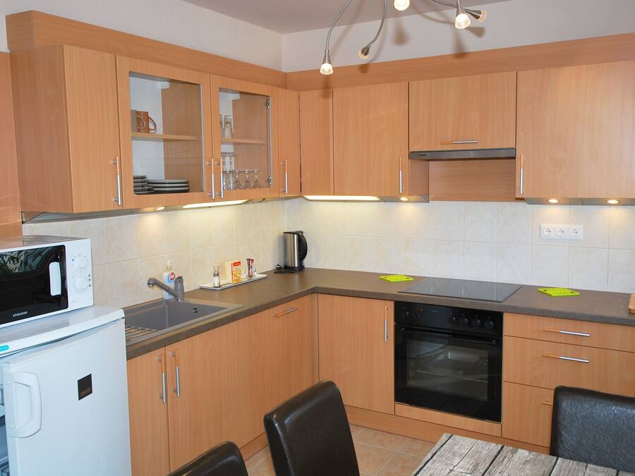 A compact kitchen with wooden cabinets, a microwave, a sink, and a stove.