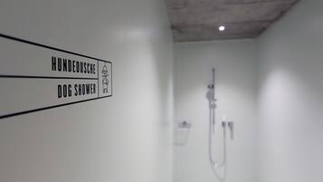 A bathroom with a sign indicating a dog shower.