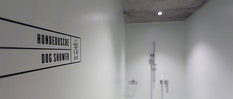 A bathroom with a sign indicating a dog shower.
